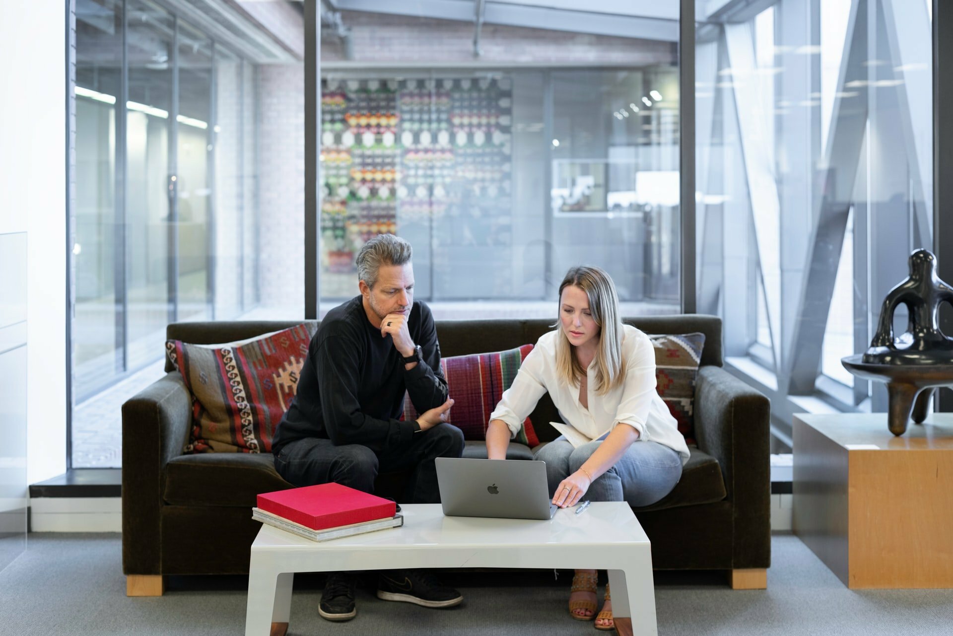 a man and a woman sitting on a couch in front of a laptop