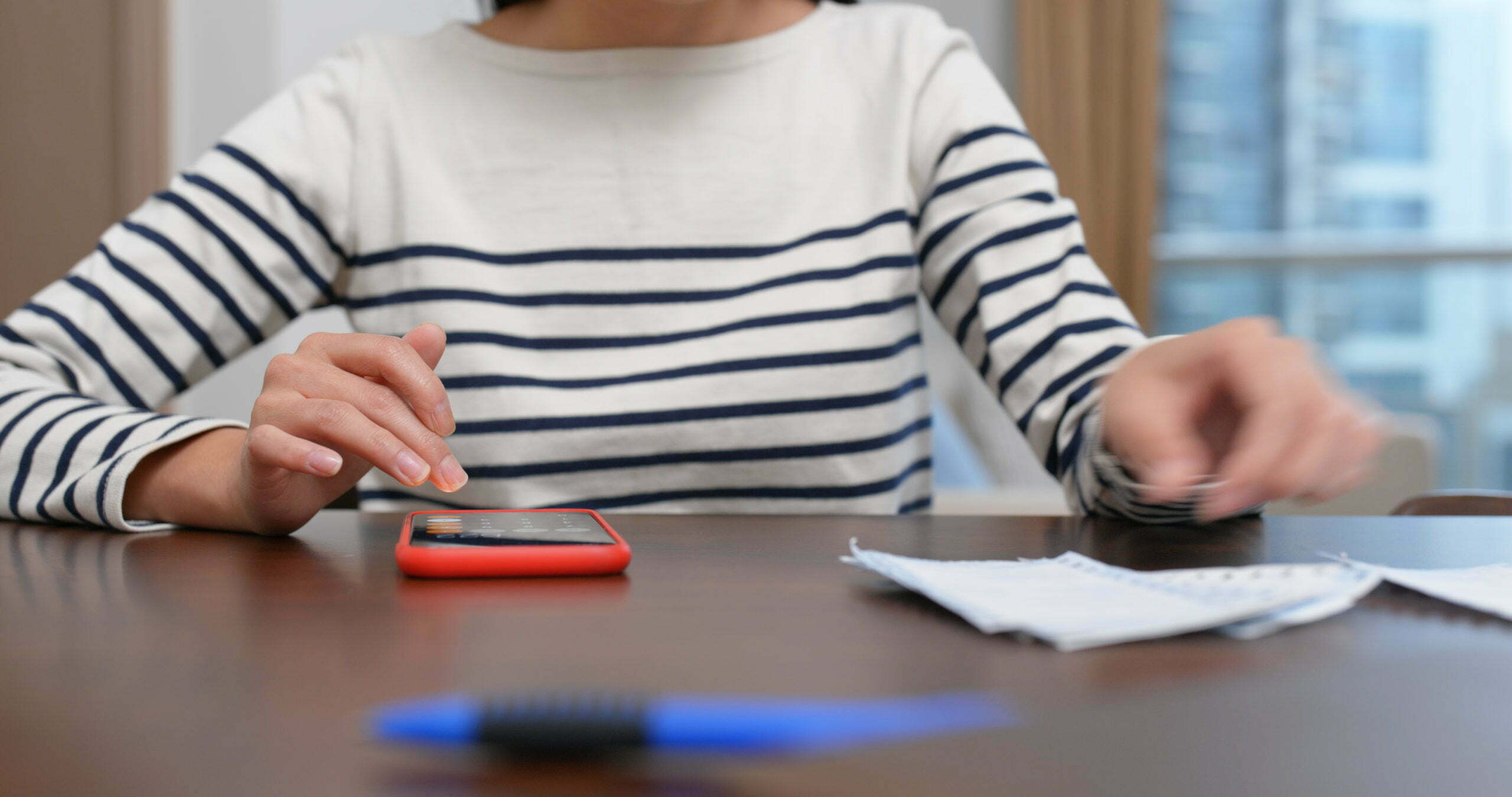 a person sitting at a table with a phone and a pen