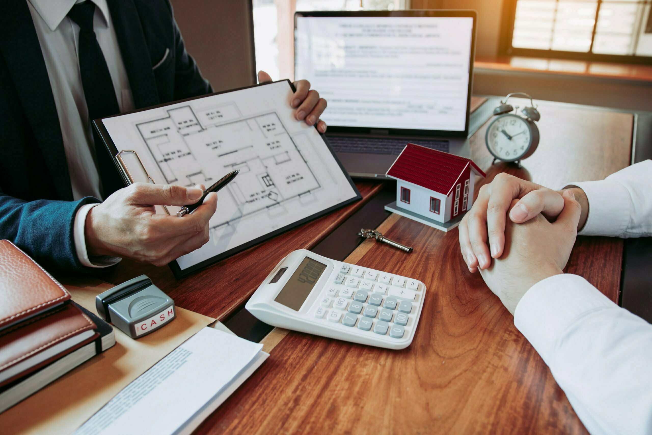 a group of people sitting at a desk with papers and a clock