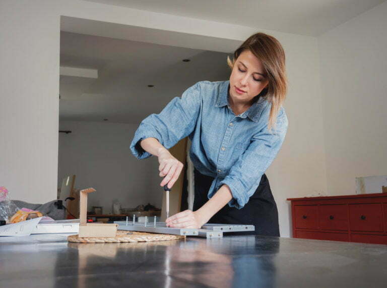 woman with screwdriver instaling a furniture at home personally